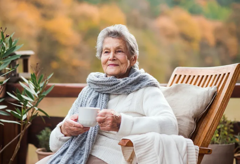 Frau mit Tasse auf einem Balkon sitzend
